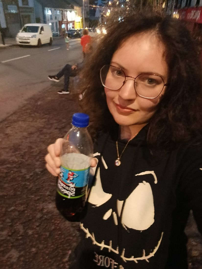Ella holding a bottle of Football Special at night