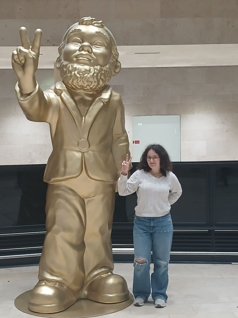 Ella doing a peace sign beside a giant gold gnome
